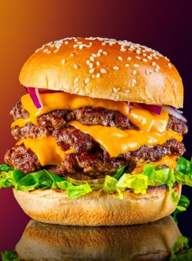 A closeup view of a tasty tower Cheeseburger isolated on a blurry background